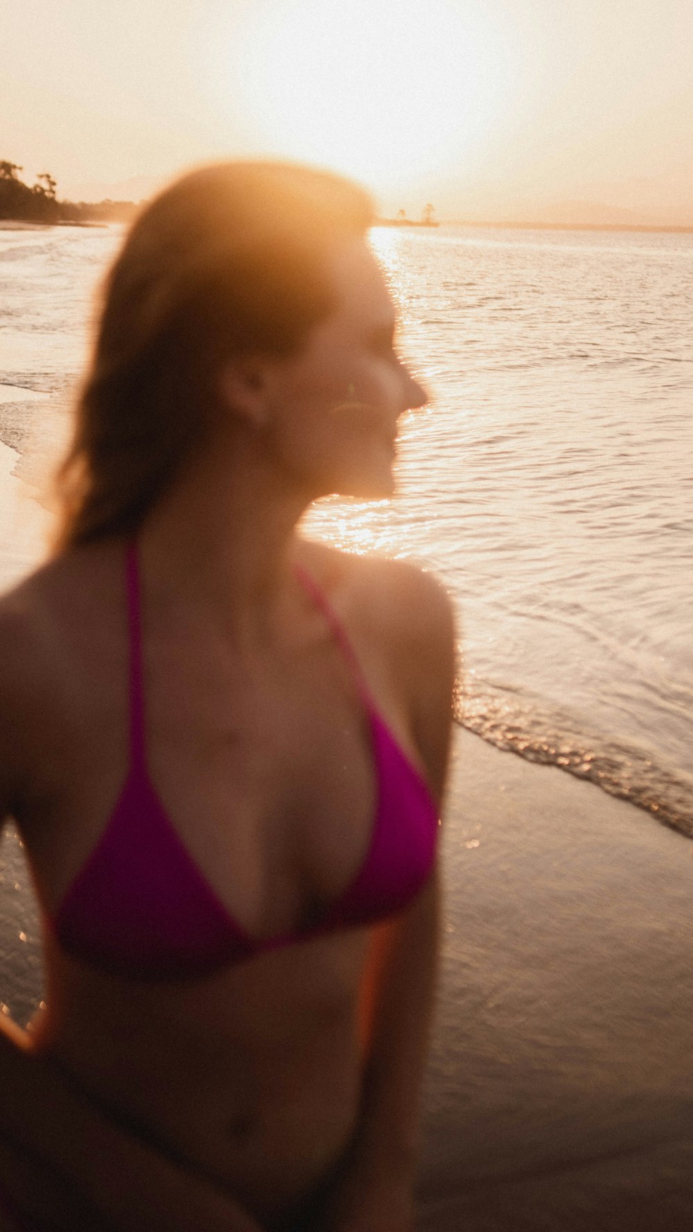 a woman in a pink bikini standing on a beach