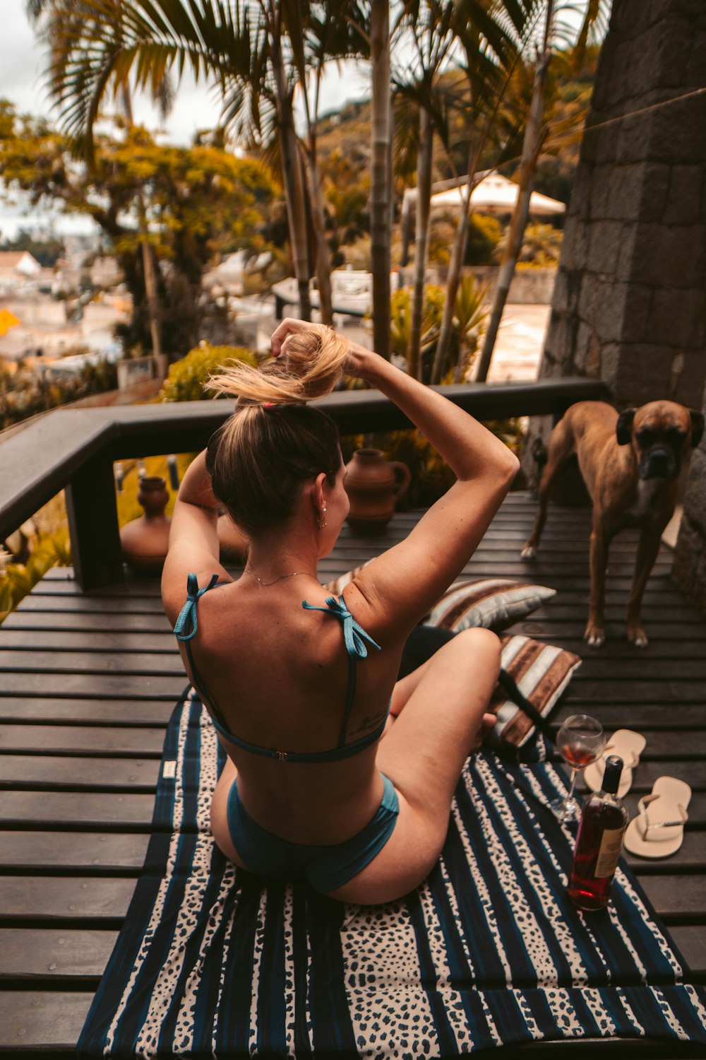 a woman in a bikini sitting on a deck next to a dog