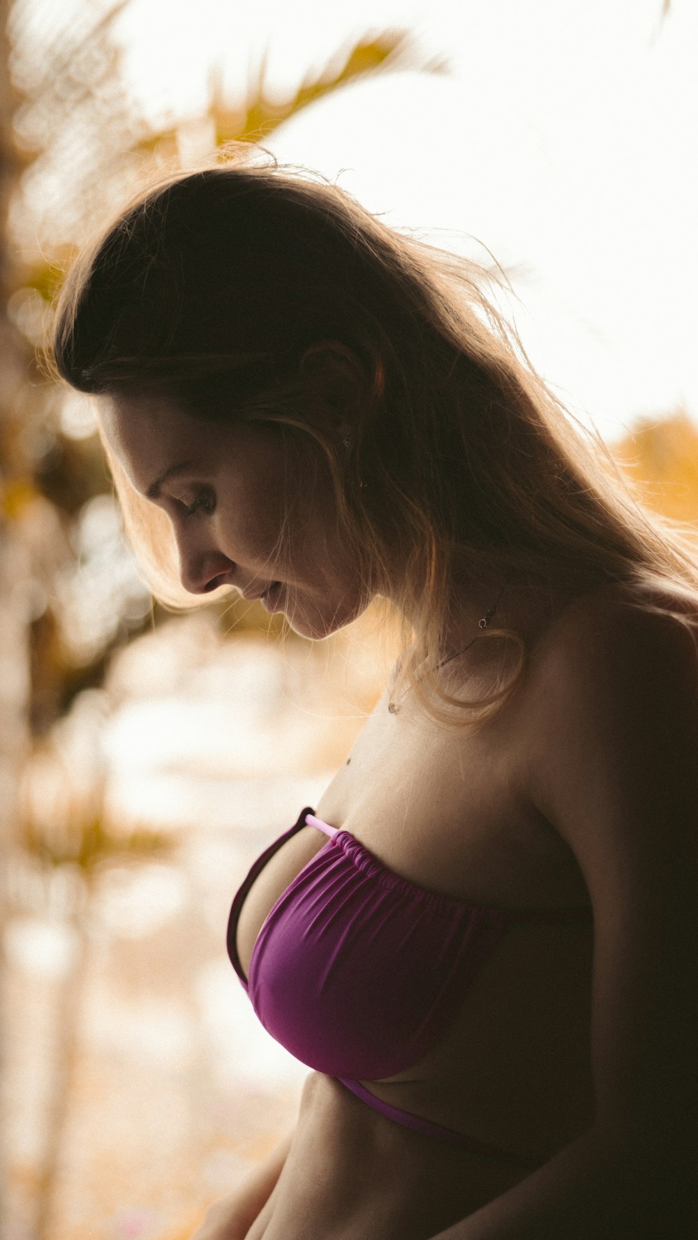 a woman in a bikini looking down at her cell phone