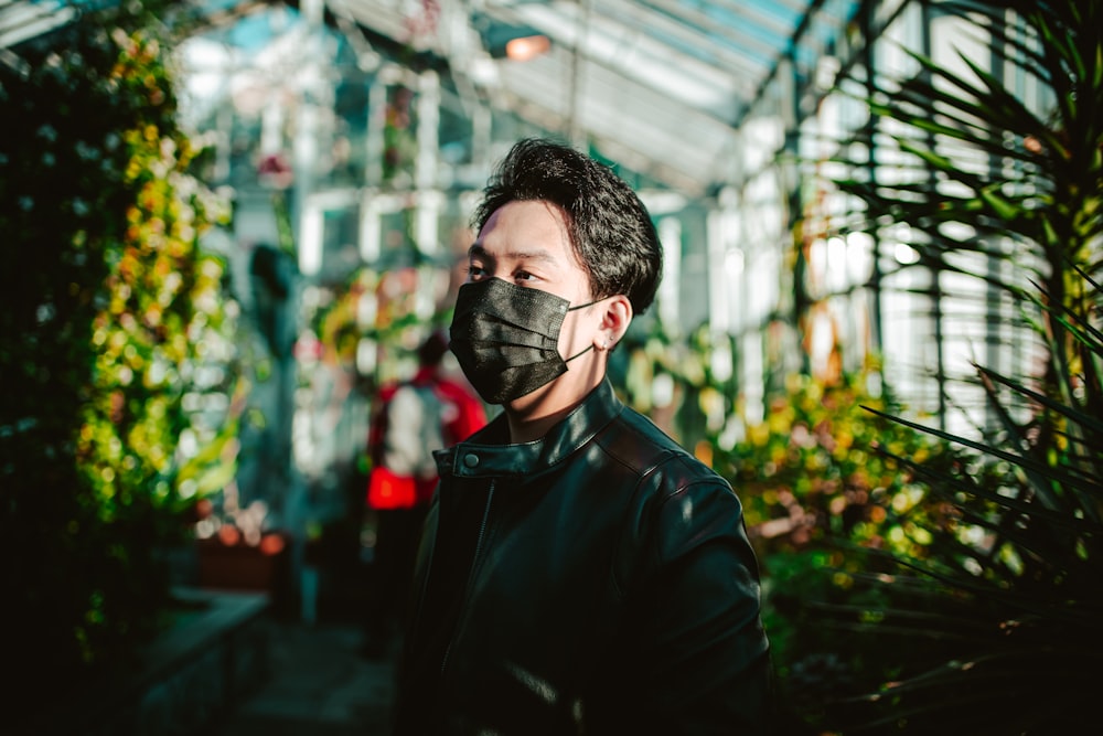 a man wearing a face mask in a greenhouse