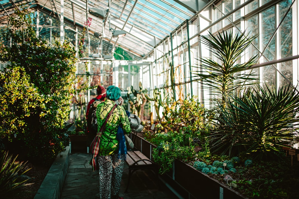 a woman in a green jacket standing in a greenhouse