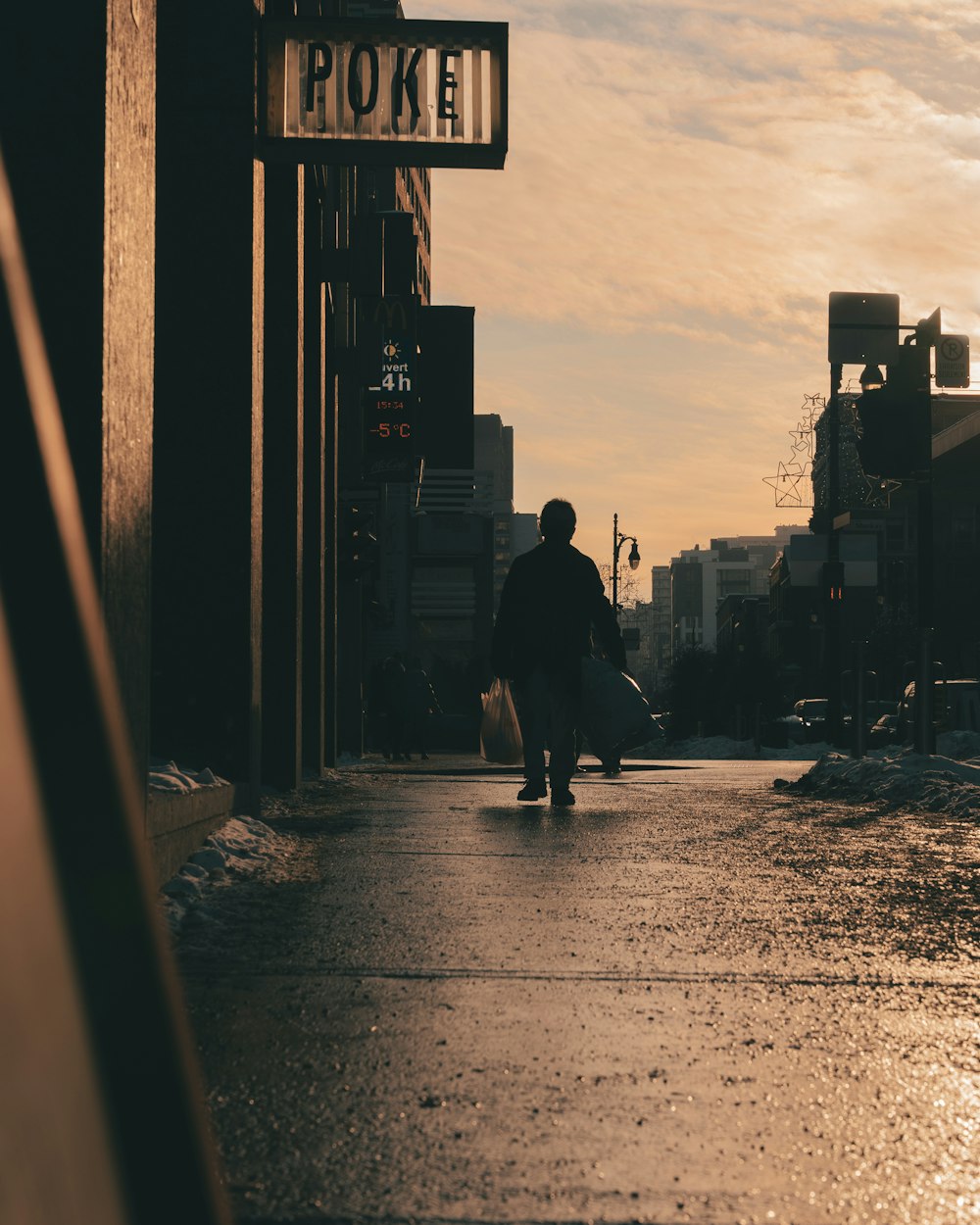 a man walking down a street holding a surfboard