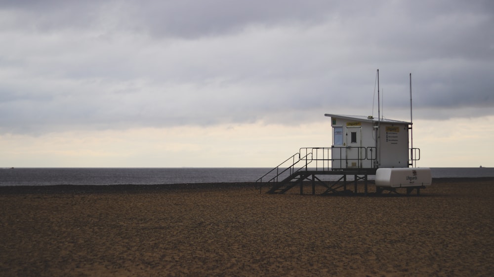 a lifeguard tower on the beach with a cloudy sky