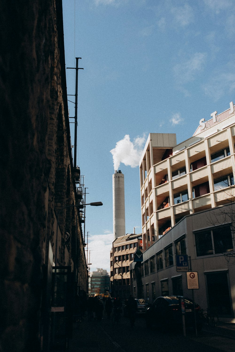 a city street with tall buildings and a smoke stack in the distance