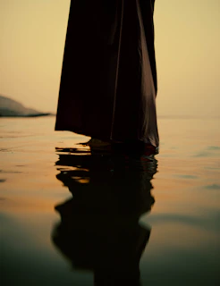 a person standing in the water with a umbrella