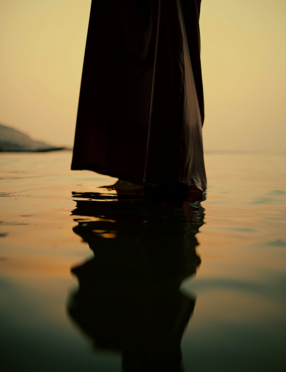 a person standing in the water with a umbrella