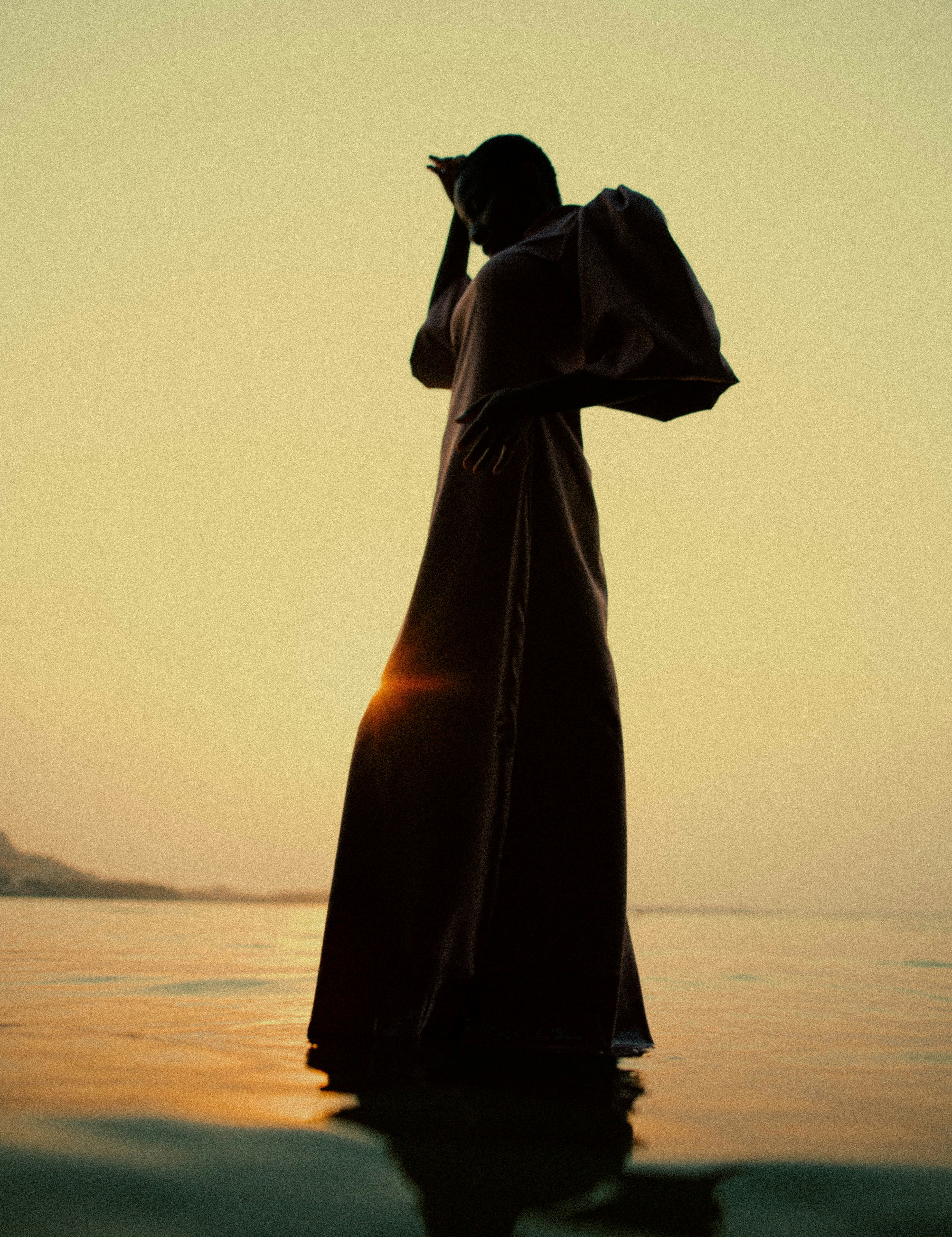 una persona in piedi nell'acqua al tramonto