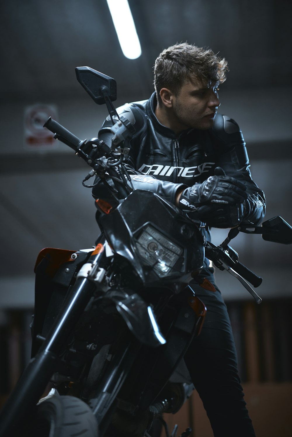 a man sitting on a motorcycle in a garage