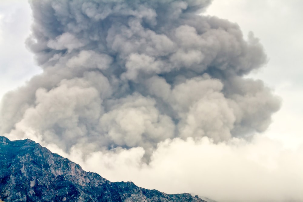 a large plume of smoke billows from a mountain