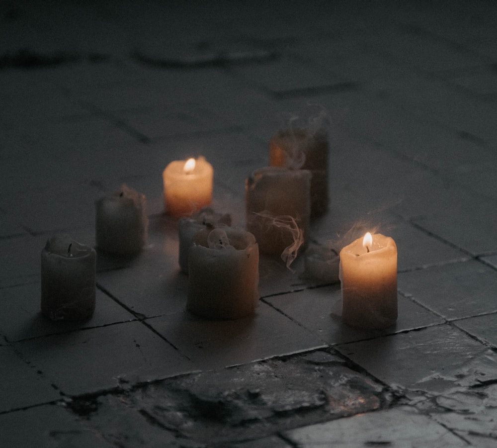 a group of lit candles sitting on top of a tiled floor