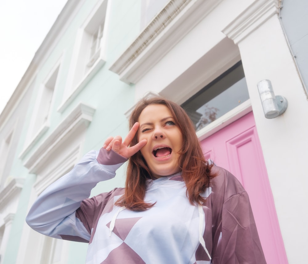 a woman standing in front of a pink door