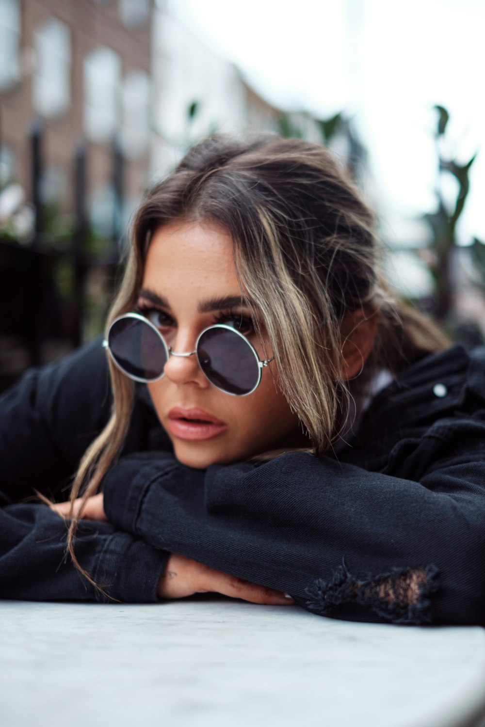 a woman wearing sunglasses leaning on a bench