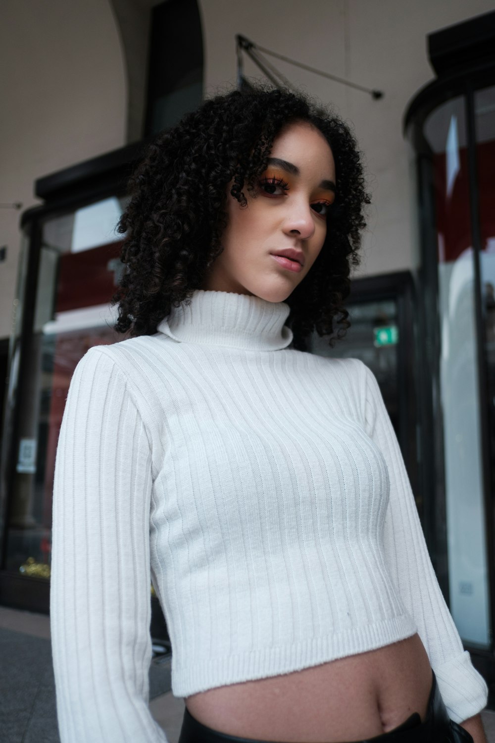 a woman wearing a white sweater and black pants