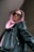 A person is wearing a pink headscarf and black leather jacket, looking up while wearing rectangular black sunglasses. The angle of the photo is from below, creating a sense of empowerment.