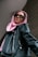 A person is wearing a pink headscarf and black leather jacket, looking up while wearing rectangular black sunglasses. The angle of the photo is from below, creating a sense of empowerment.