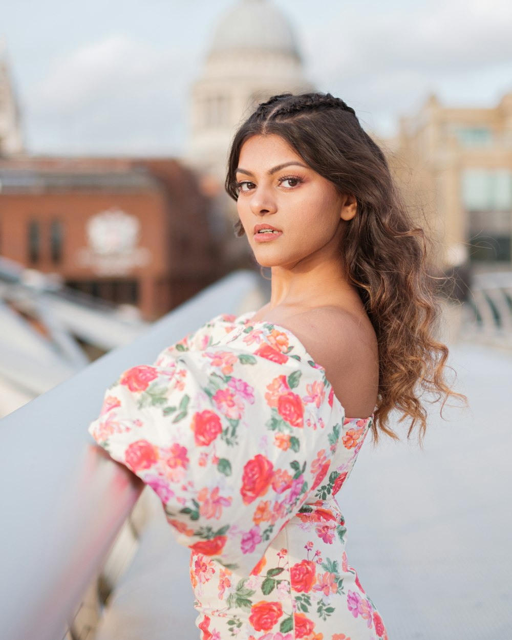 a woman in a floral dress leaning against a wall