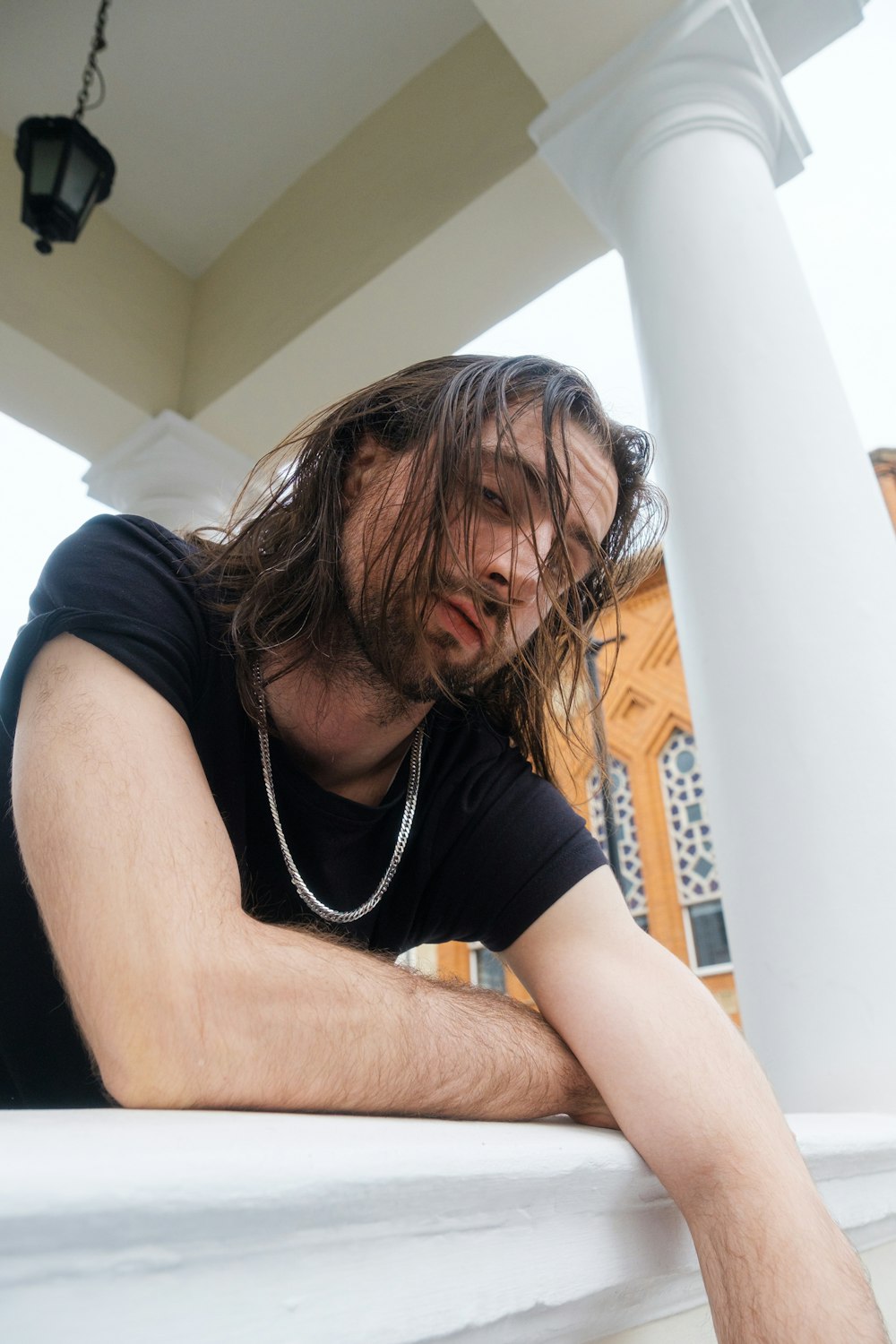 a man with long hair sitting on a porch