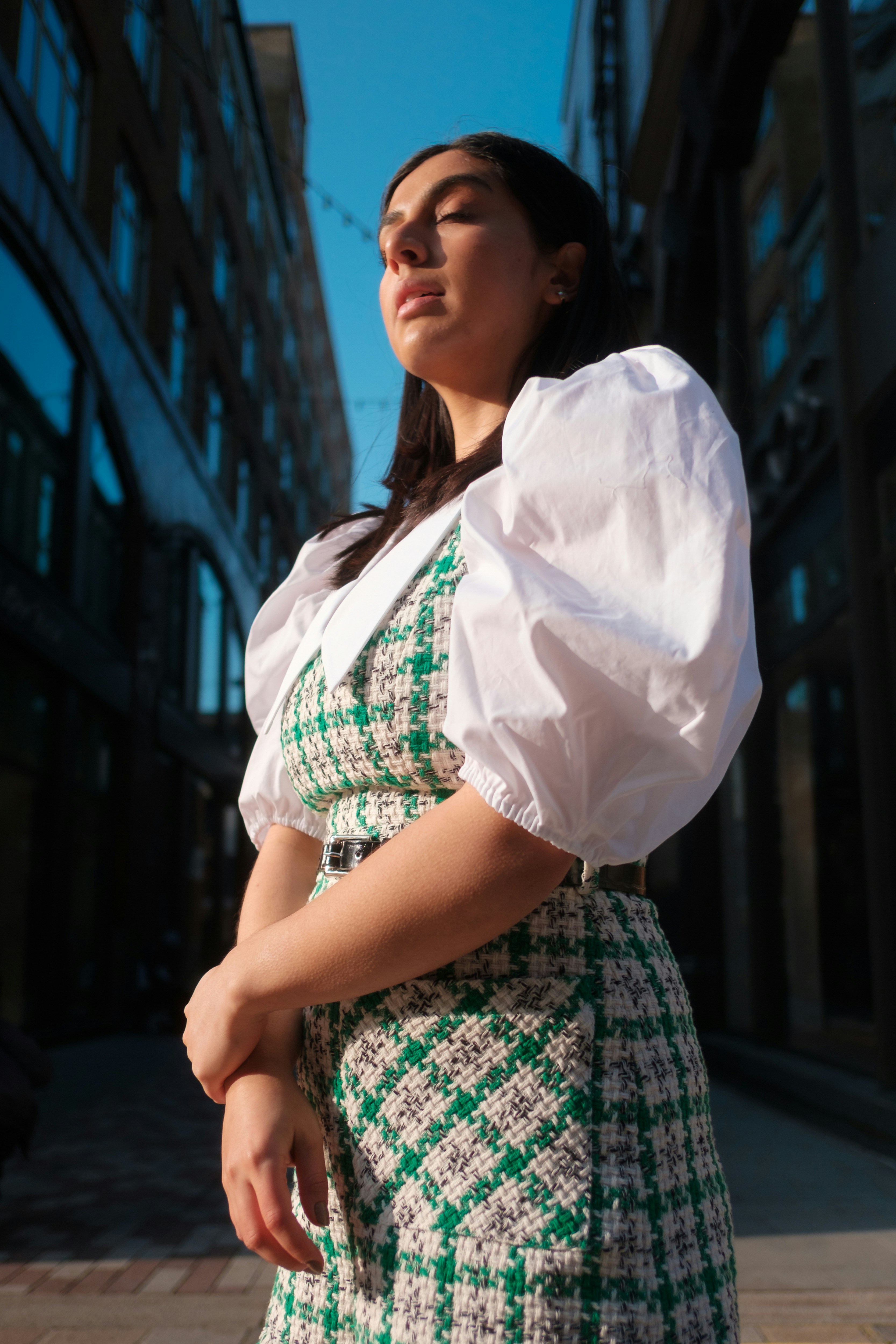 A woman in a green and white dress standing on a sidewalk photo – Free ...