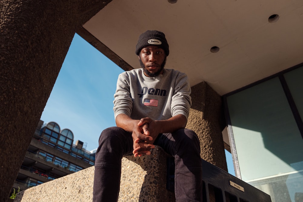 a man sitting on a ledge in front of a building