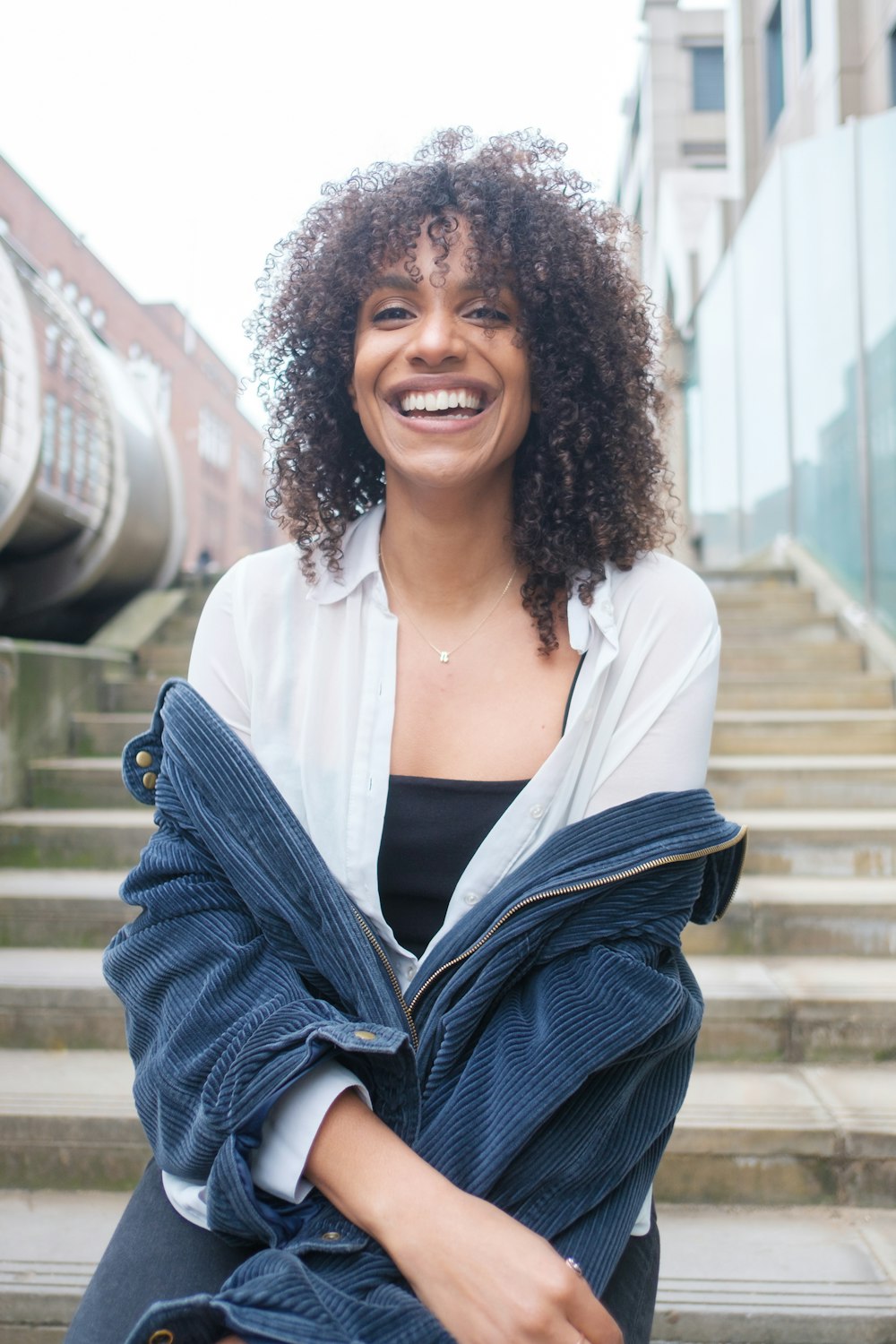 a smiling woman sitting on the steps of a building