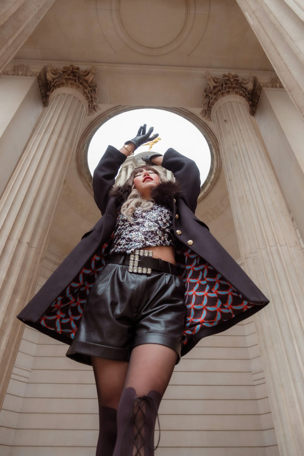 a woman in a short skirt and jacket standing in front of a building