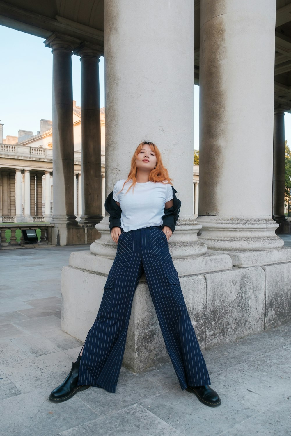 a woman leaning against a pillar with her legs crossed