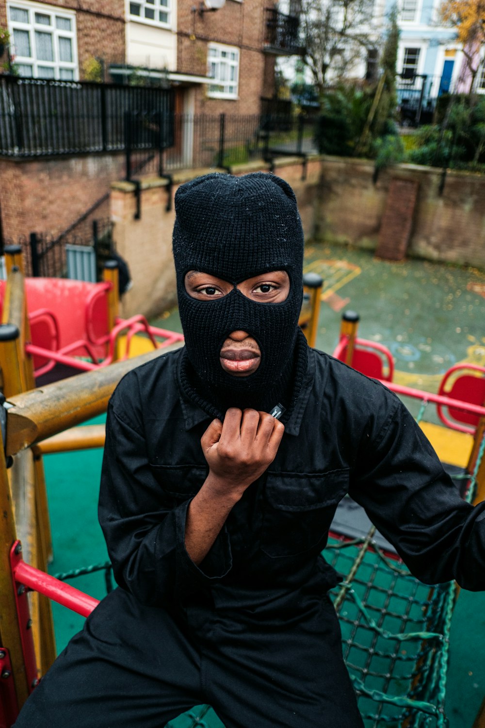 a man in a black mask sitting on a playground