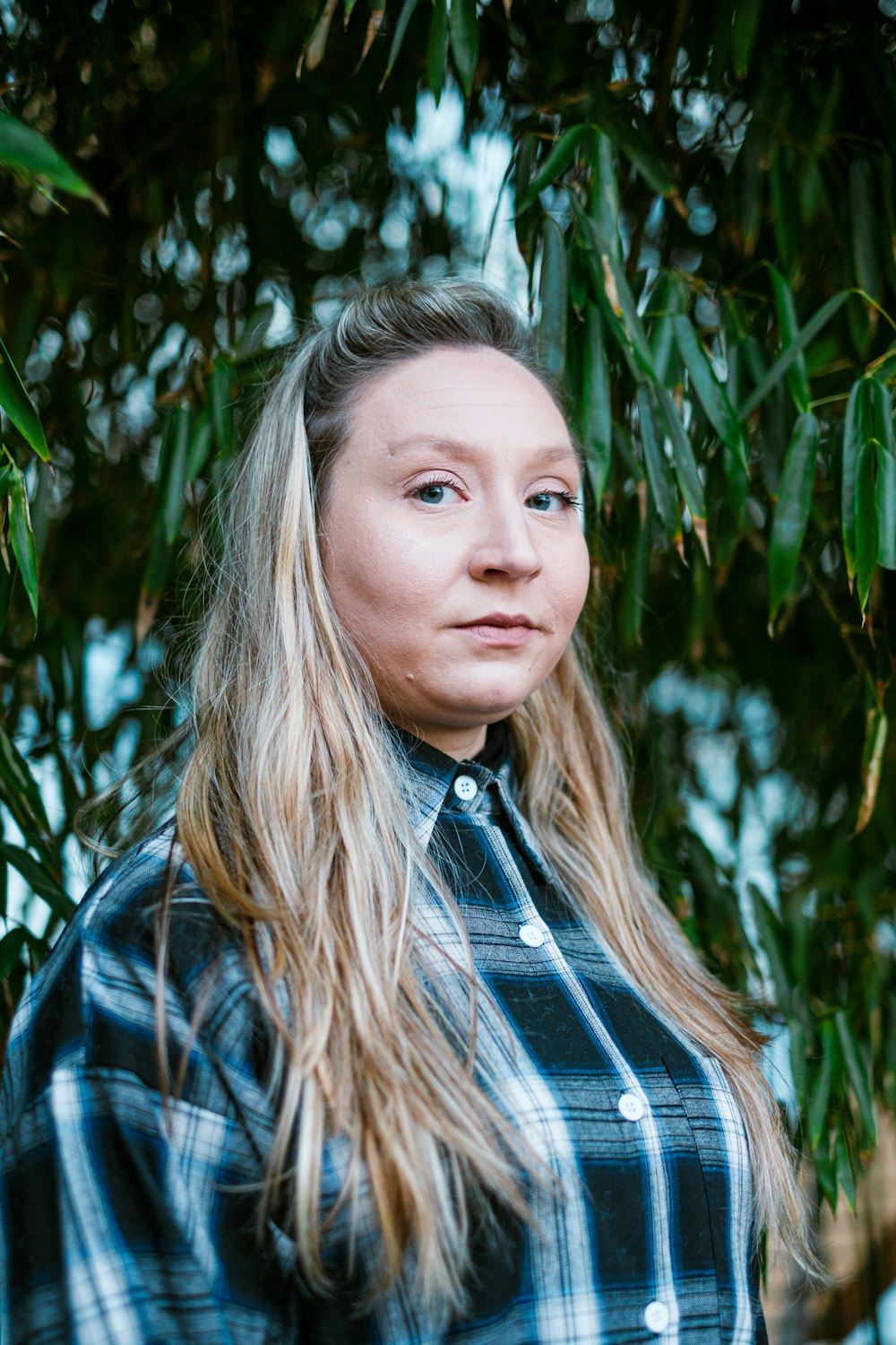 a woman with long hair standing under a tree