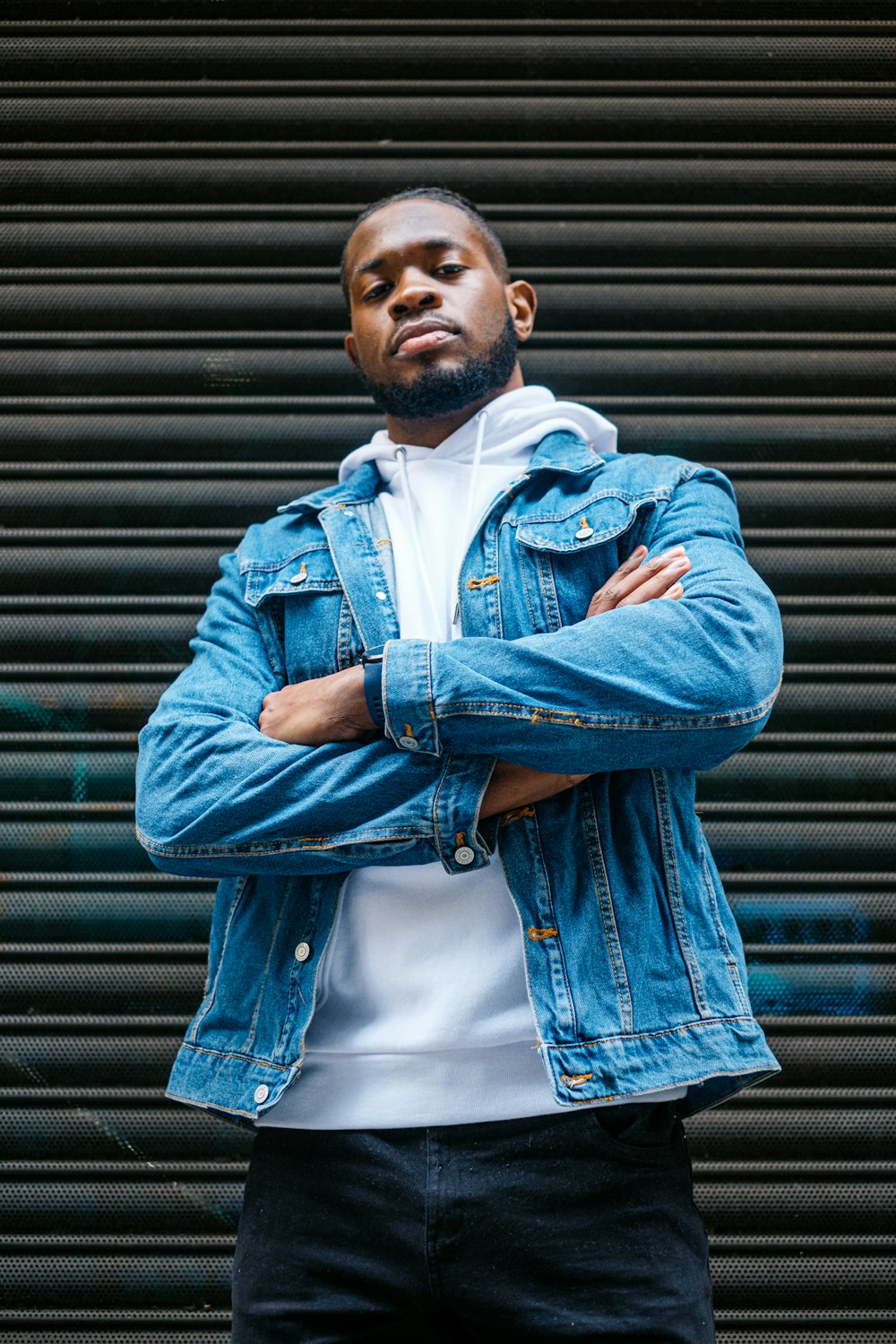 a man with his arms crossed standing in front of a garage door