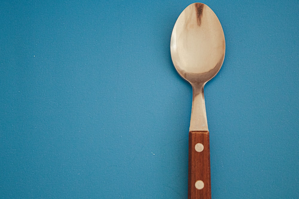 a spoon with a wooden handle on a blue surface