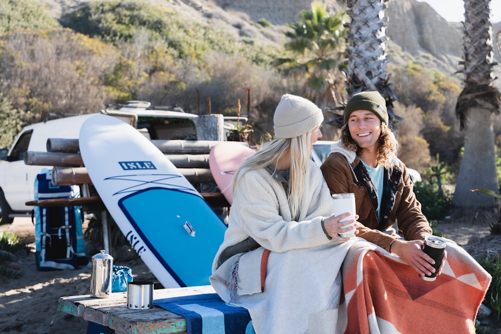 a couple of women sitting on a bench next to a surfboard