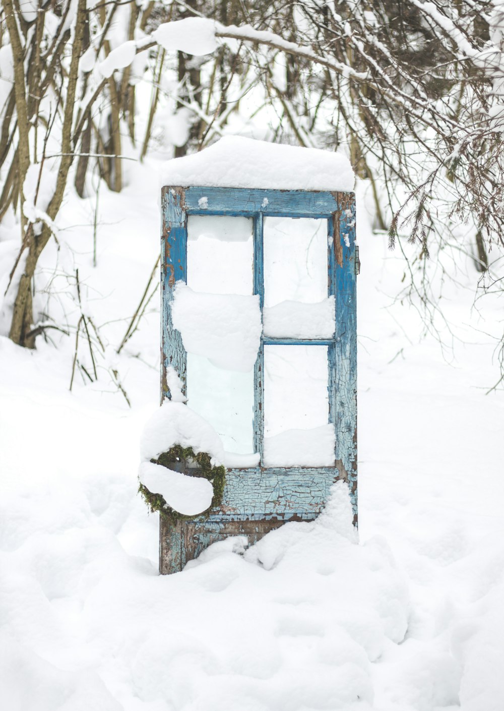 Una porta sfondata seduta nel mezzo di una foresta coperta di neve