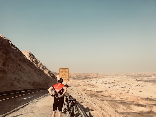 A cyclist reaching out for support on a scenic road.