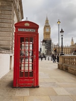 a red phone booth sitting on the side of a street