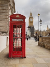 a red phone booth sitting on the side of a street