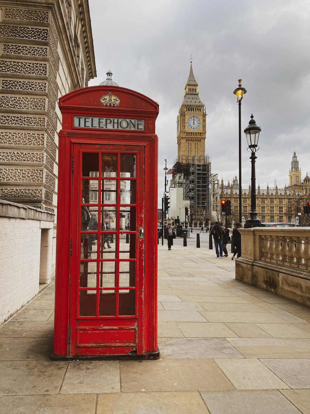 a red phone booth sitting on the side of a street