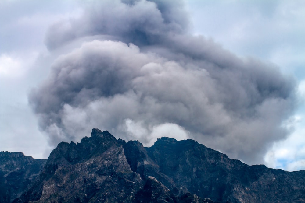 a large plume of smoke billows from the top of a mountain