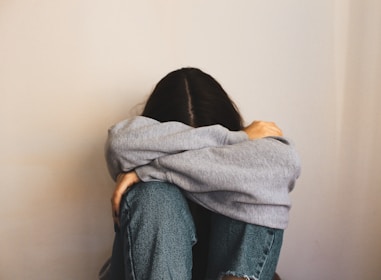a woman sitting on the floor with her arms wrapped around her head