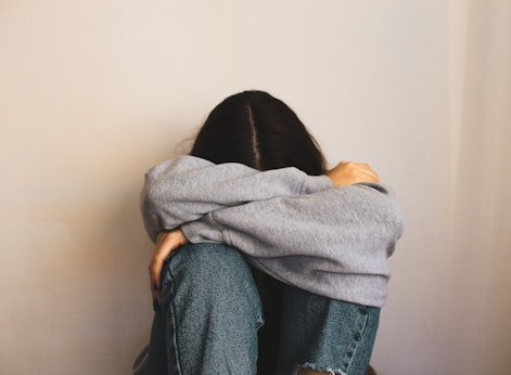 a woman sitting on the floor with her arms wrapped around her head