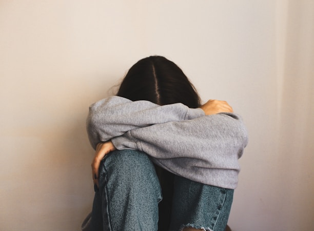 a woman sitting on the floor with her arms wrapped around her head