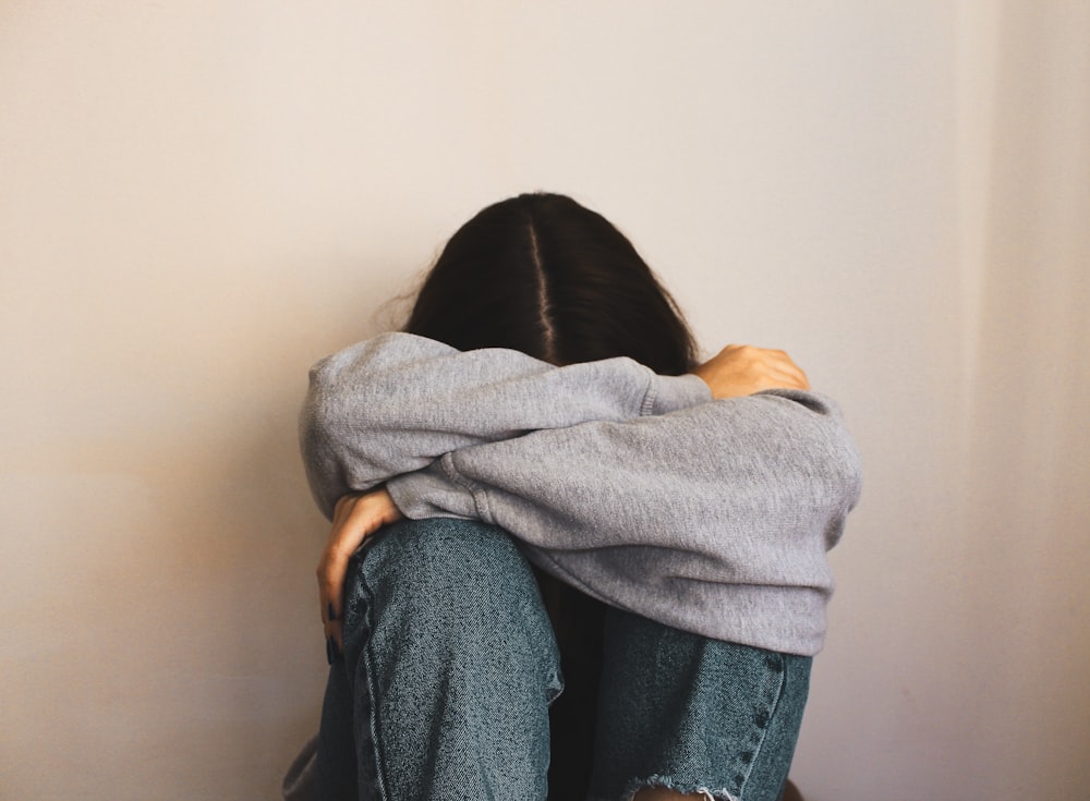 a woman sitting on the floor with her arms wrapped around her head