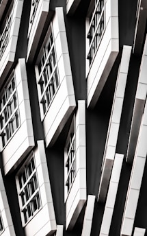 A series of white-framed windows arranged in an asymmetric pattern on a black facade, creating a modern, geometric appearance.
