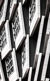 A series of white-framed windows arranged in an asymmetric pattern on a black facade, creating a modern, geometric appearance.