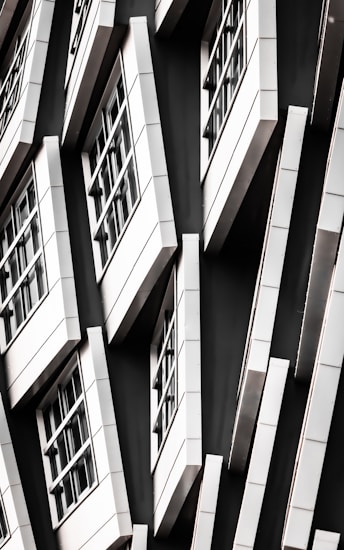 A series of white-framed windows arranged in an asymmetric pattern on a black facade, creating a modern, geometric appearance.