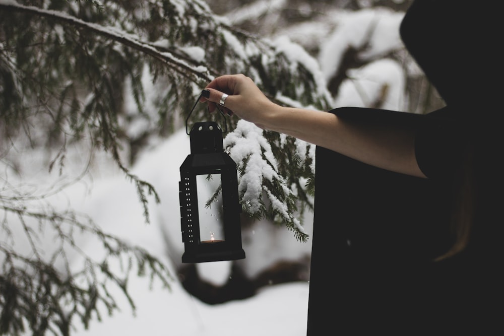 a person holding a lantern in the snow