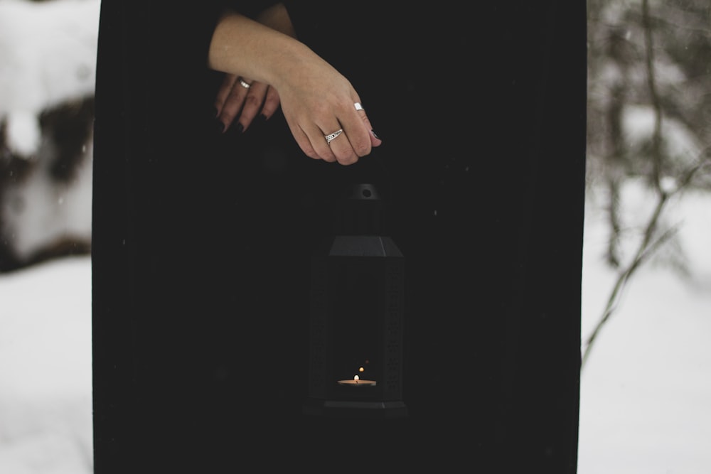 a woman in a black dress holding a lit candle