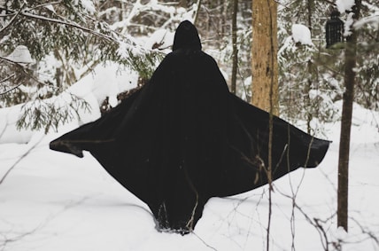 a person in a black cloak in the snow