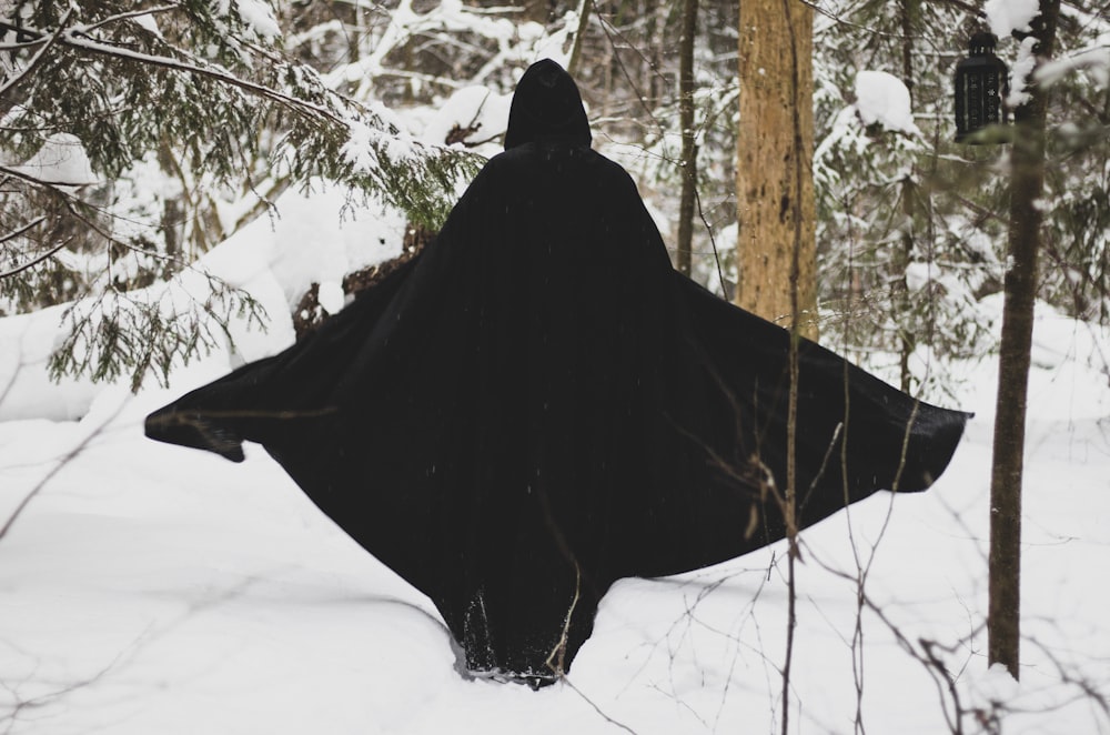 a person in a black cloak in the snow