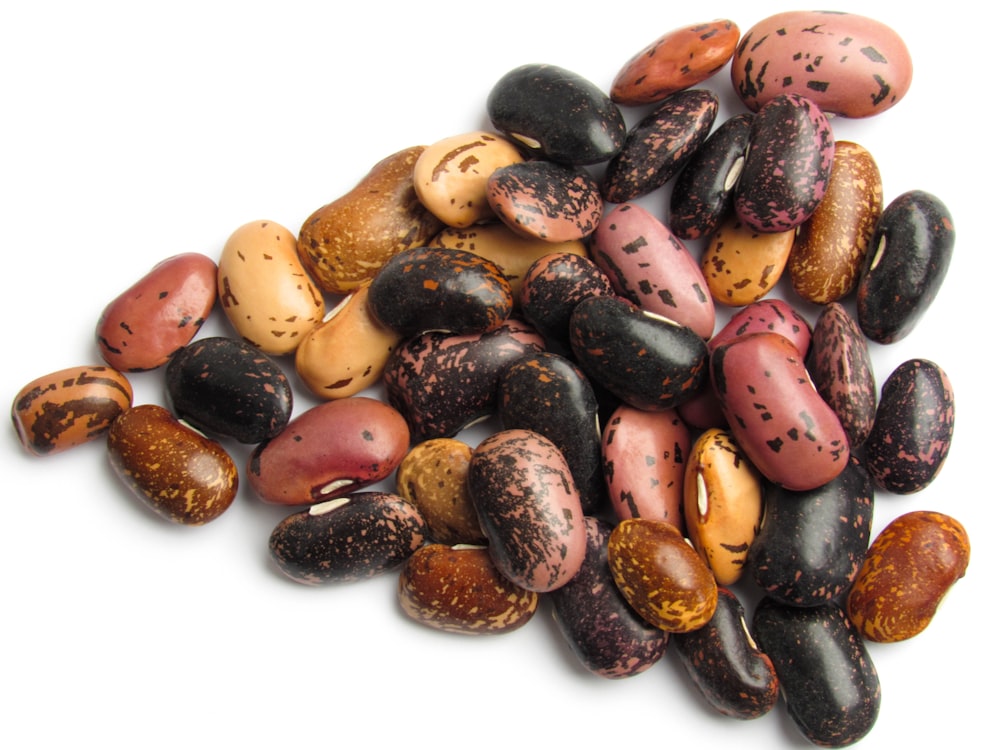 a pile of different colored beans on a white surface