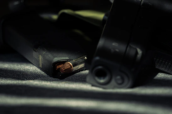 Close-up of a sleek integrally suppressed firearm resting on a wooden workbench with tools and ammo nearby.